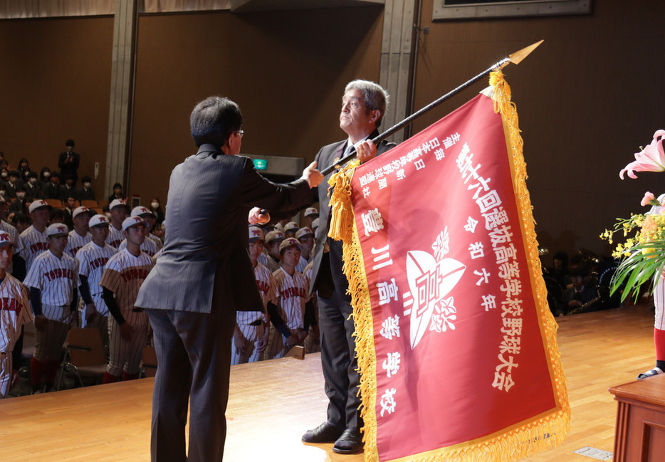 毎日新聞中部本社の鯨岡秀紀代表からセンバツ旗を受け取る豊川の石田潤校長＝愛知県豊川市で２０２４年２月２０日、塚本紘平撮影