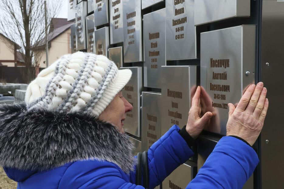 夫の名前が書かれた慰霊碑の前で泣き崩れるオリガ・コシャンチュクさん＝24日、ウクライナ・ブチャ（共同）
