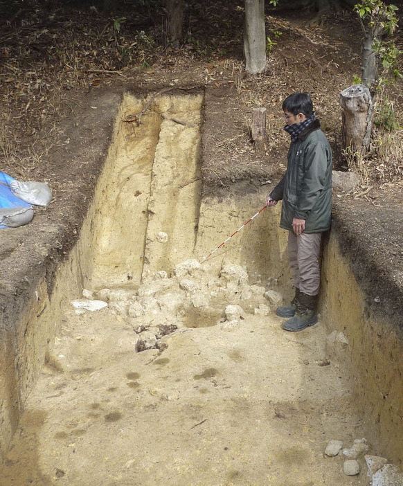 塚穴古墳で発掘された墳丘端で、出土した凝灰岩を示す宮内庁の担当者＝2日、大阪府羽曳野市