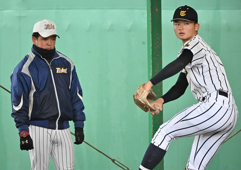 佐藤選手の投球練習を見つめる安田コーチ（左）＝平川義之撮影