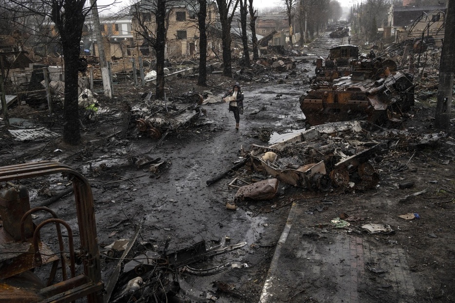 ウクライナ・ブチャで、破壊されたロシア軍の戦車などの間を歩く女性＝2022年4月（AP＝共同）