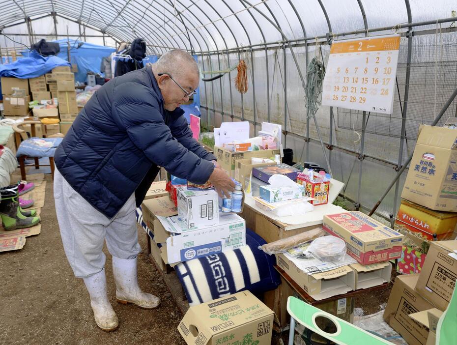 届いた支援物資を整理する、ビニールハウスで自主避難所を運営する保靖夫さん＝25日午前、石川県輪島市