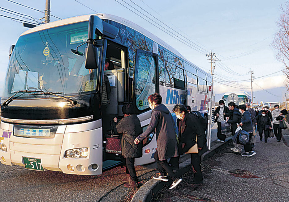 輪島行きのバスに乗り込む避難者＝２４日午前７時、加賀市中島町