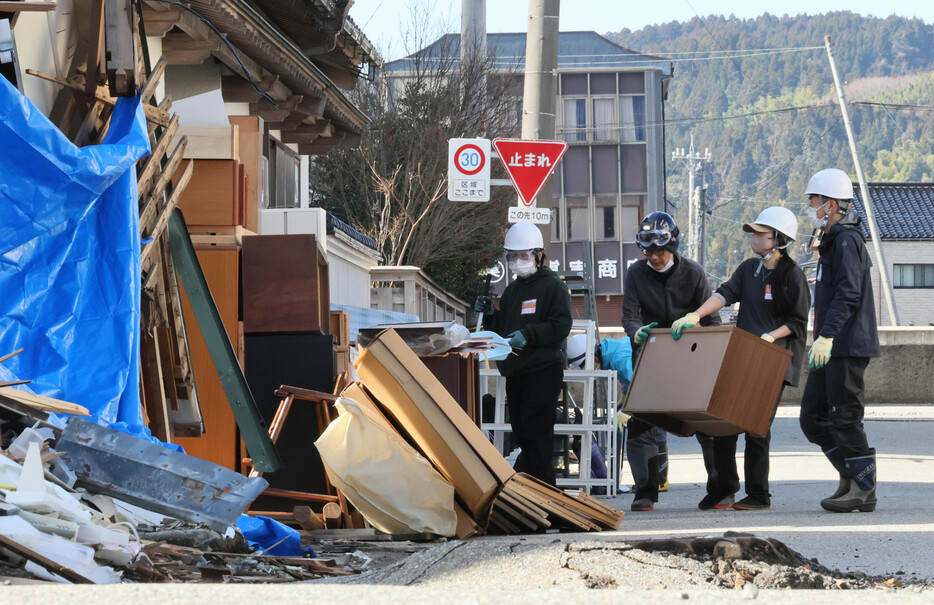 損壊した建物から荷物を運び出すボランティアスタッフ＝１１日午前１１時半、輪島市河井町