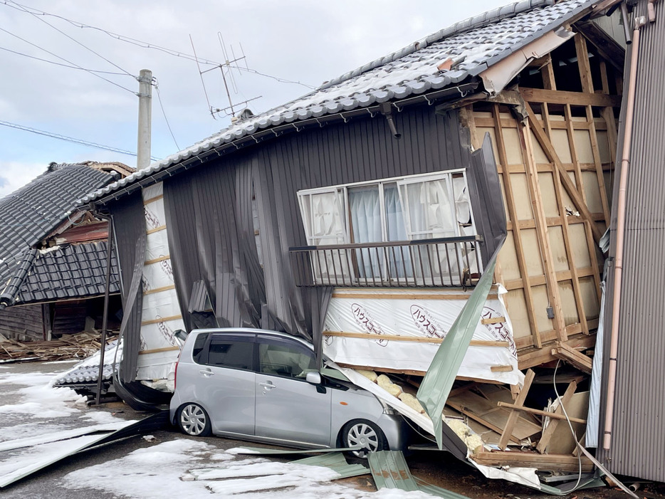 倒壊した住宅と下敷きになった車＝1月27日、石川県輪島市