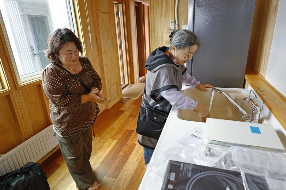 能登半島地震の被災者向けに建設された応急仮設住宅に入り、蛇口からの水に笑みを浮かべる大下澄子さん（右）と娘の尚美さん＝3日午前、石川県輪島市