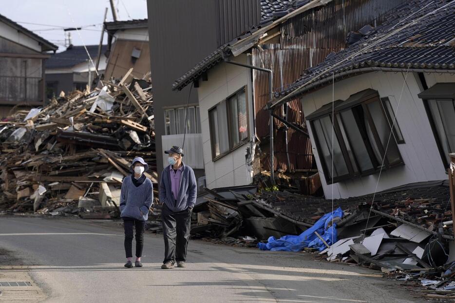 地震で甚大な被害が出た石川県珠洲市の宝立町地区を歩く夫婦＝29日午前