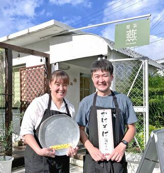 「かどや」から受け継いだメニューの札やお盆を手にする「喫茶燕」店主の宮下和幸さん（右）、妻咲乃さん＝１６日、浦添市牧港