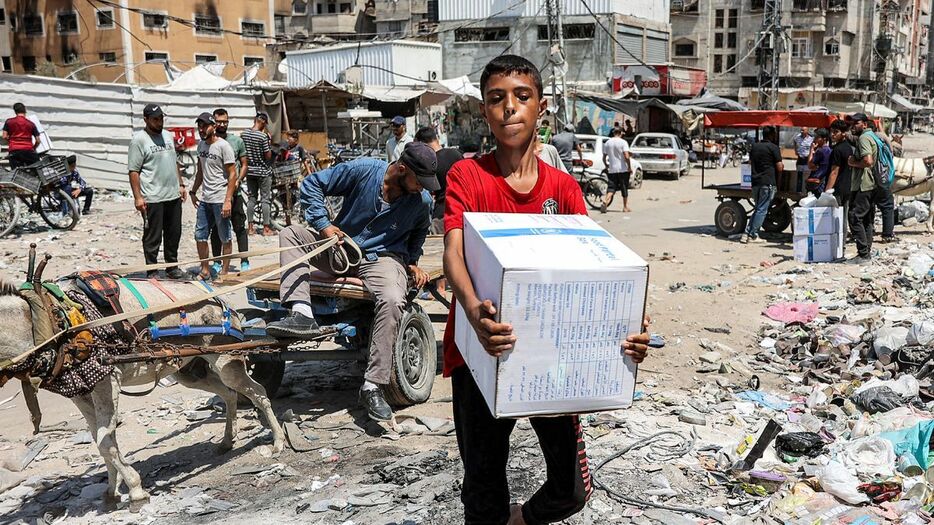 国連パレスチナ難民救済事業機関（ＵＮＲＷＡ）の支援物資を運ぶ少年＝８月、パレスチナ自治区ガザ地区中部