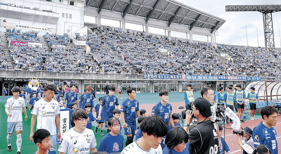 スタンドを埋め尽くすサポーターを背に入場するカターレの選手＝富山県総合運動公園陸上競技場