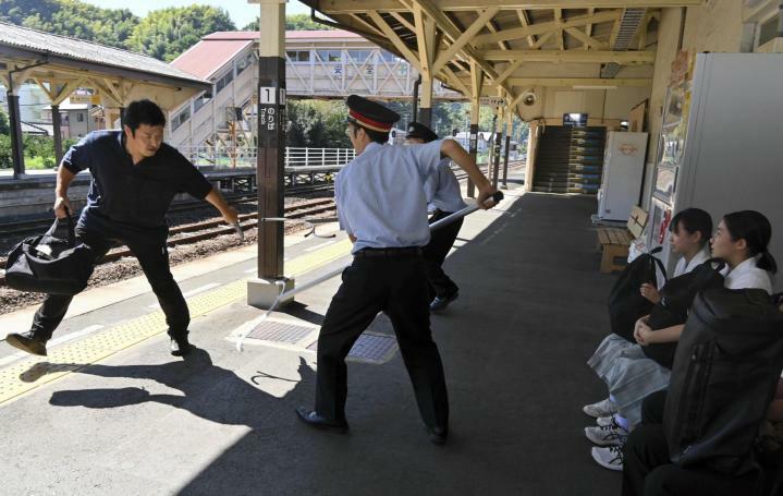 刃物を持った男（左）をさすまたでけん制し、高校生の安全を確保する駅員たち