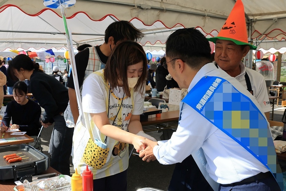 宮ふれあい祭りに訪れ、支持を求める候補者＝佐世保市城間町（写真は一部加工）