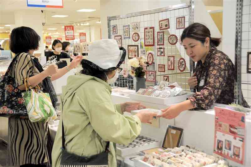 鶴屋百貨店で始まった「フランス展」で、木製のアクセサリーボタンを選ぶ買い物客＝23日、熊本市中央区