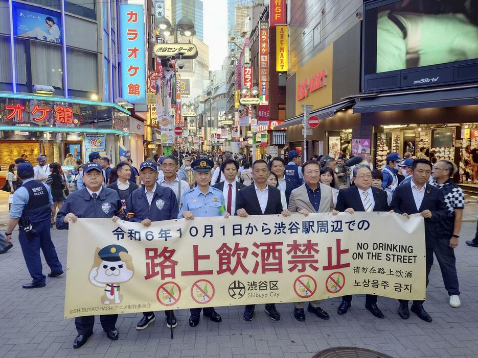 「路上飲酒禁止」と書かれた横断幕を持って練り歩く東京都渋谷区長の長谷部健氏（中央）ら＝1日午後、東京都渋谷区