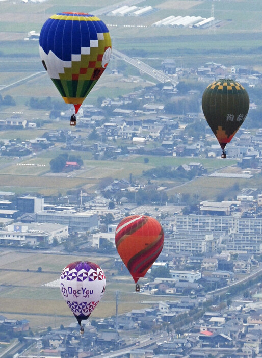 佐賀インターナショナルバルーンフェスタの競技フライトが始まり、嘉瀬川河川敷を目指す色とりどりの熱気球＝佐賀市で2024年10月31日午後3時53分、本社ヘリから上入来尚撮影