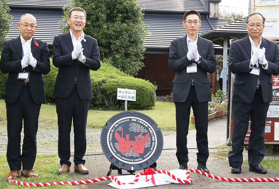 「はにわマンホール」を除幕した竹上市長（左から2人目）ら＝外五曲町の鈴の森で