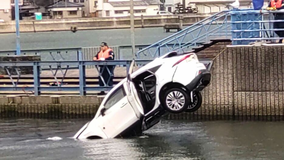 現場からクレーンで引き上げられる車