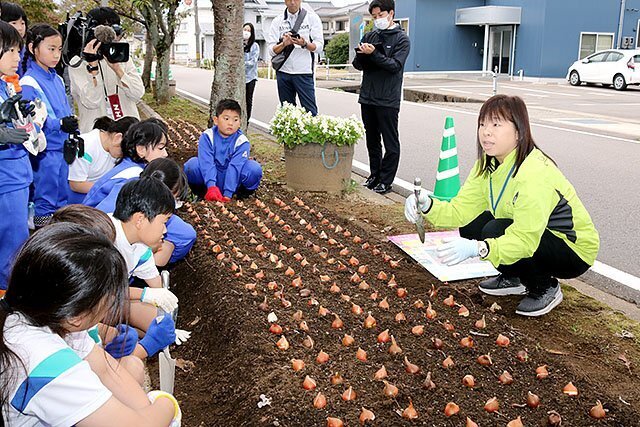 児童に球根の植え方を教える三上さん（右）