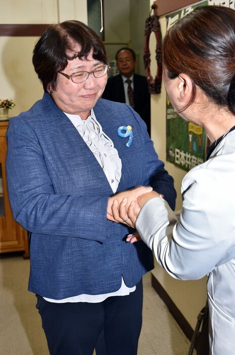 涙をこらえながら関係者と握手する高橋さん＝28日午前1時39分