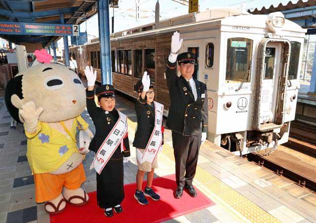 観光特急「海幸山幸」運行１５周年の出発式で、列車に合図をする一日駅長ら＝１２日午前、ＪＲ宮崎駅