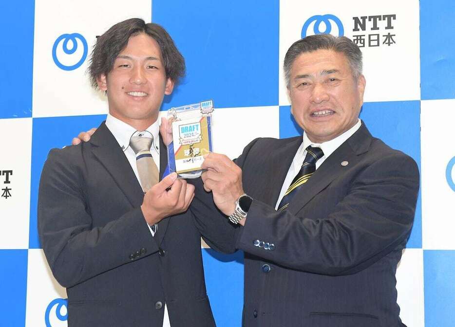 指名挨拶の際に、担当した1位指名のNTT西日本・伊原陵人（左）と笑顔で写真におさまる熊野輝光スカウト。伊原をはじめ多くの選手を虎に導いてきた