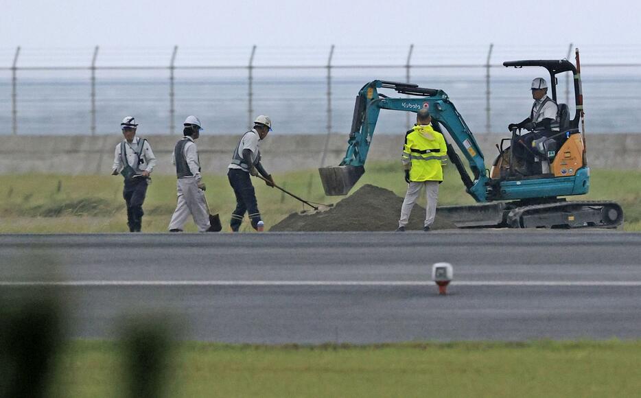 不発弾の爆発で陥没した宮崎空港の誘導路で作業する関係者＝2日午後5時39分