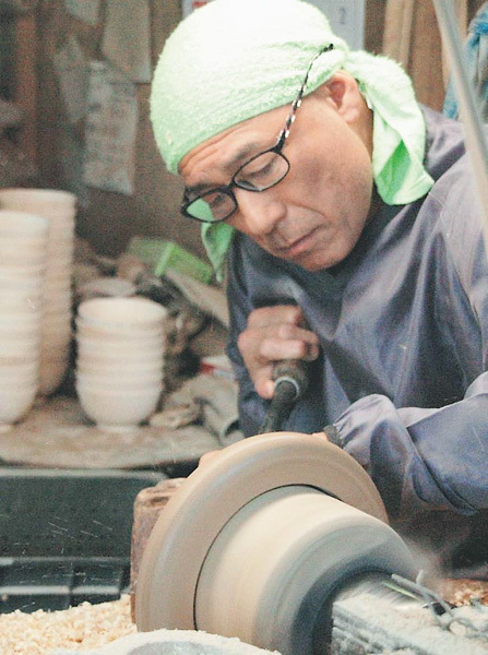 給食用の漆器となる木地をひく新山さん