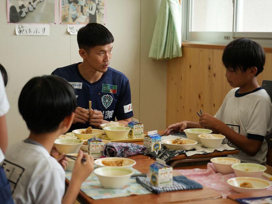 照葉はばたき小で児童と給食を食べながら話すJ1福岡・奈良（奥）＝クラブ提供