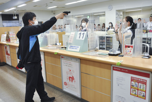 【拳銃で脅して金を要求する強盗犯＝四日市市諏訪町の三菱UFJ銀行四日市支店で】