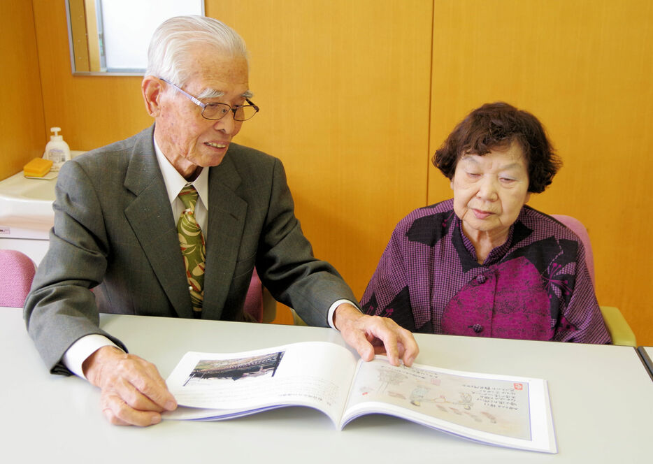 ８０年近い歳月を経て再会した黒田さん（左）と田畑さん。再会のきっかけとなった絵本を手にする＝京都府南丹市園部町・園部中