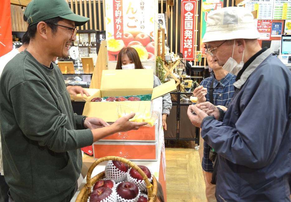 「恋するみつ子」を来客にPRする荒谷直大会長（左）＝25日、二戸市