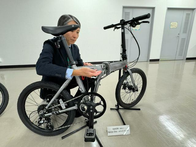 使用中止が呼びかけられた折りたたみ自転車は、フレームとヒンジ部分の溶接部（指で指している部分）に欠陥がみつかった=東京都港区の国民生活センター