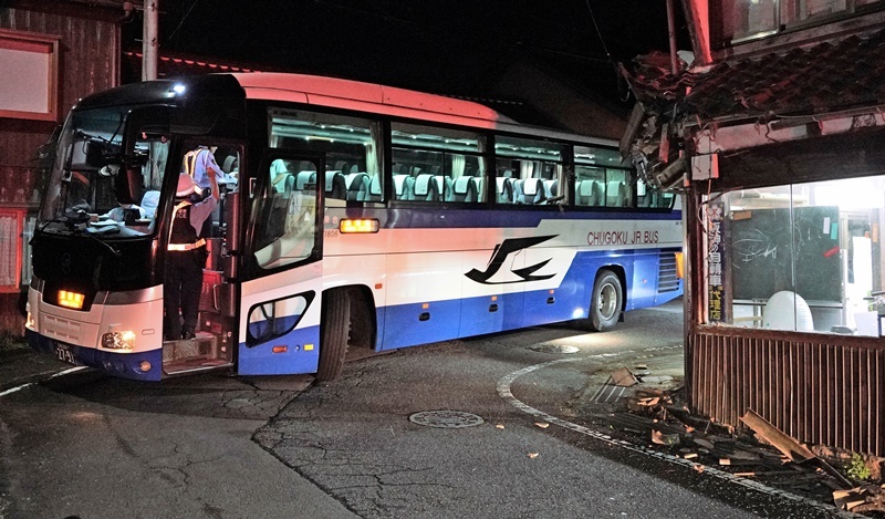 事務所（右）の屋根に衝突した高速バス＝２１日午後１１時、島根県邑南町市木