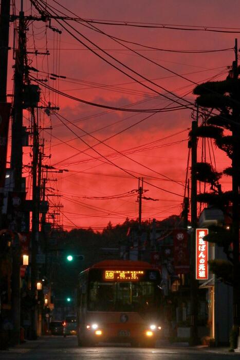 夕陽で真っ赤に染まった西の空。夕闇に沈む城下町をバスが明かりをともして走り抜ける＝２４日午後５時２５分、丹波篠山市呉服町から撮影