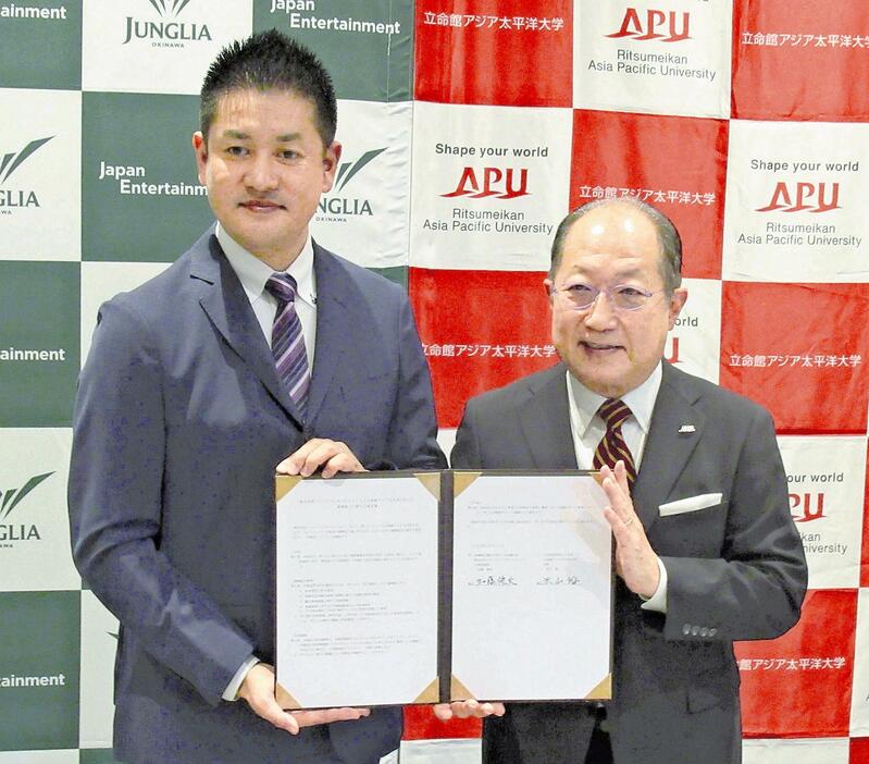 包括協定を結んだジャパンエンターテイメントの加藤CEO（左）とAPUの米山学長（21日、福岡市で）