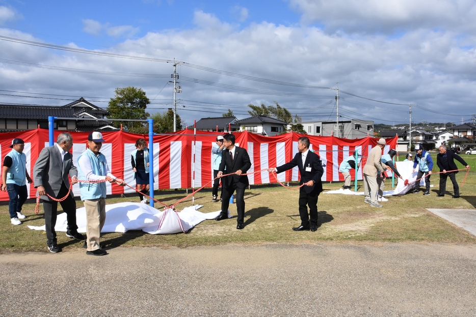 除幕して鉄棒とぶらさがりトレーナーを披露する関係者=岡山県津山市で