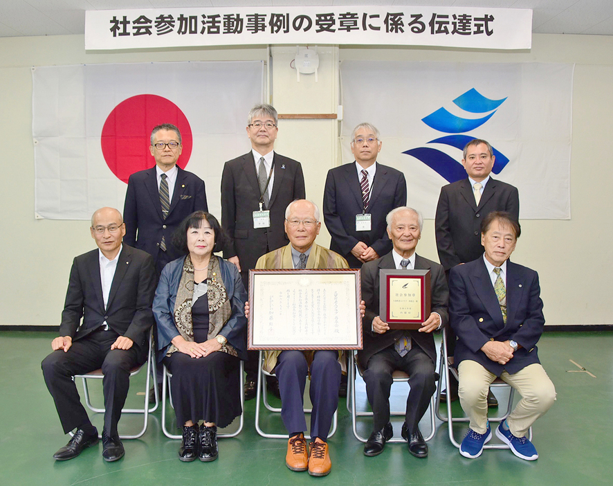 内閣府の社会参加活動事例団体に選出された「久里町老人クラブ・再春会」の中原輝久会長（前列中央）ら＝18日、鹿児島県奄美市名瀬の県大島支庁