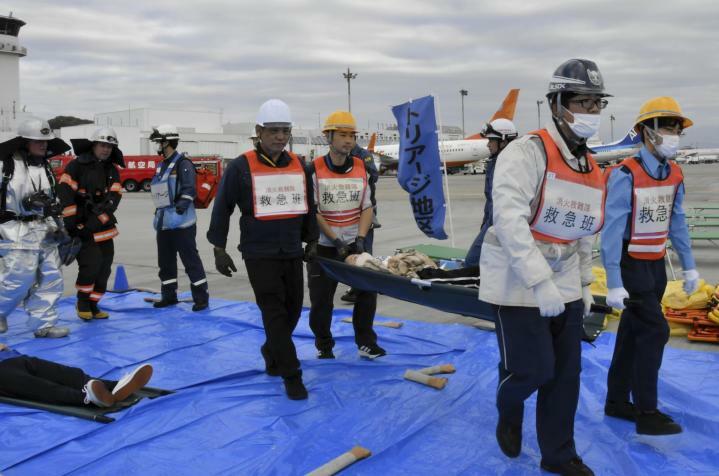 航空機事故を想定し、負傷者役を担架で運ぶ訓練参加者＝23日午後、松山空港駐機場（撮影・薬師神亮太）