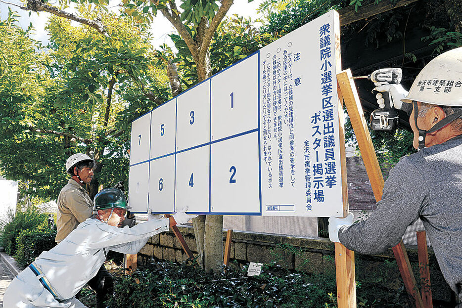 ポスター掲示場を設営する作業員＝１０日午前１１時、金沢市役所前