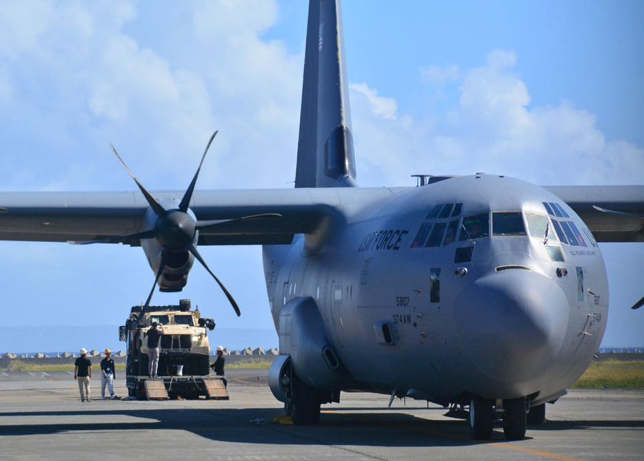 米軍のC130輸送機から下ろした米海兵隊の軍用車をトレーラーに乗せる作業員ら＝22日、鹿児島県奄美市笠利町