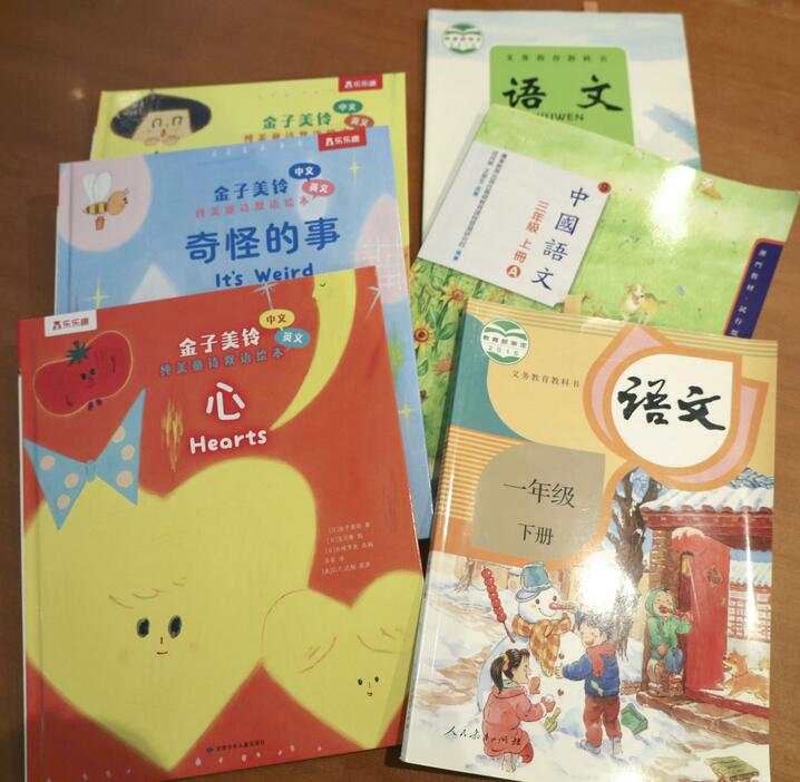 中国語に翻訳された金子みすゞの絵本（左側）と、詩が掲載された中国の教科書