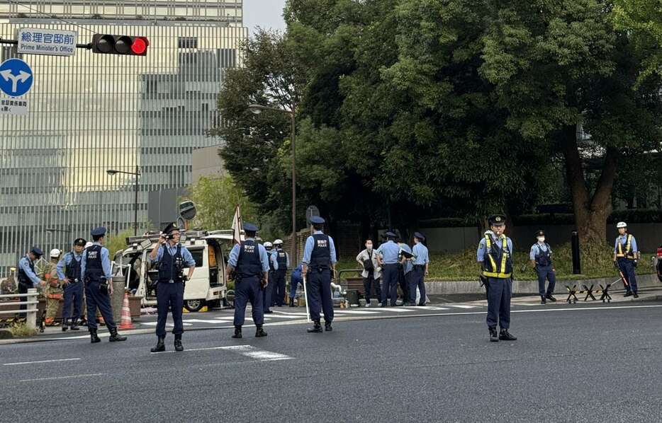 首相官邸に突っ込んだとみられる車を調べる警察官ら＝19日早朝（大渡美咲撮影）