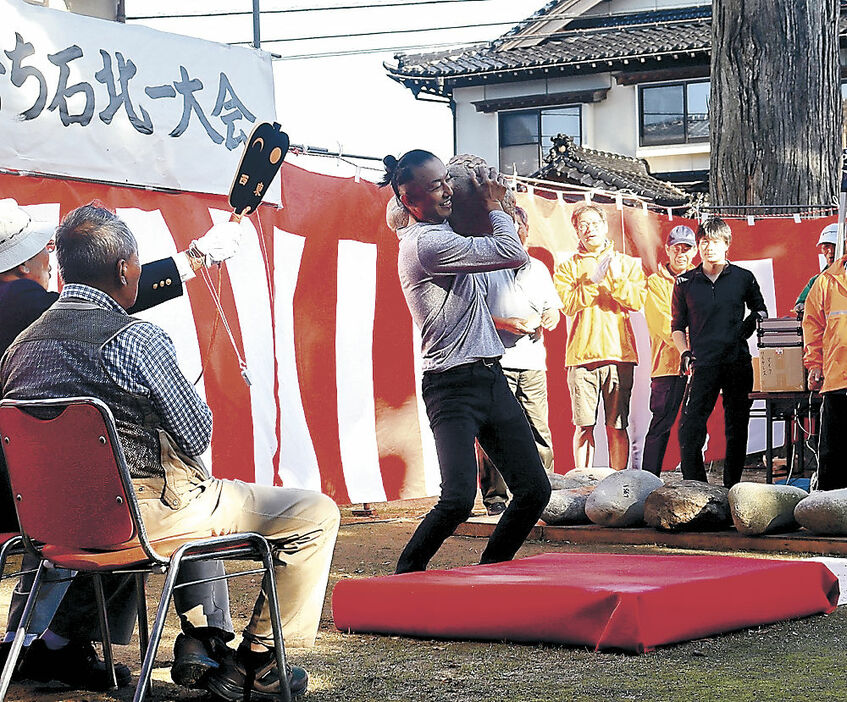 石を持ち上げる大会出場者＝小矢部市北一の住吉神社