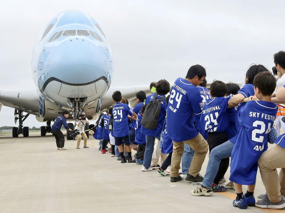 成田空港で行われたイベントで、世界最大のジェット旅客機を綱で引っ張る小学生と保護者ら＝6日午前