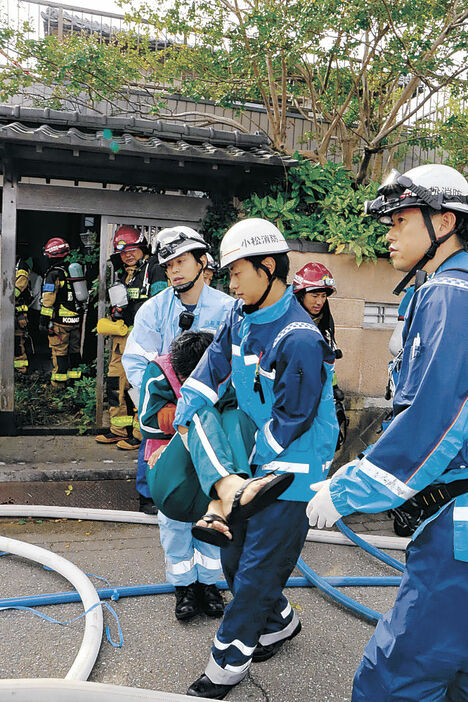 けが人役を運び出す消防署員＝小松市沖町