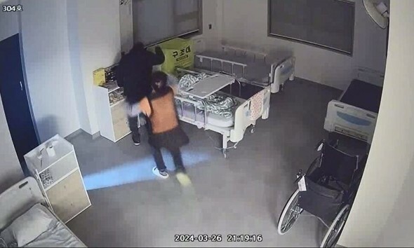 公州市のN療養院で、入所してわずか一日の89歳のMさんが、両手を縛られている間に同部屋の高齢者K氏（82）に暴行され、療養保護士が慌てて止めに入っている=CCTV映像