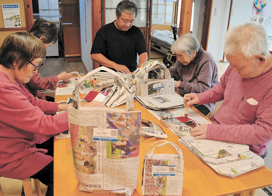 新聞エコバッグを作る利用者と伊藤さん（中央）