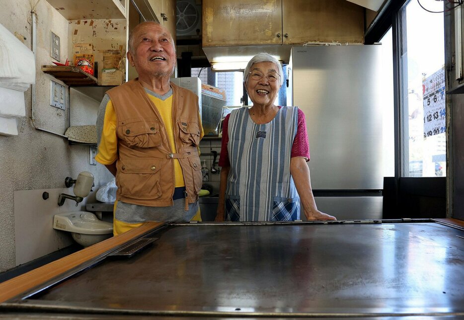 店の鉄板の前で59年間の思い出を語る敏子さん（右）と昇さん