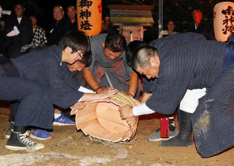 「樽引き神事」でたるを地面に勢いよく打ち付ける氏子ら＝三田市加茂、加茂神社