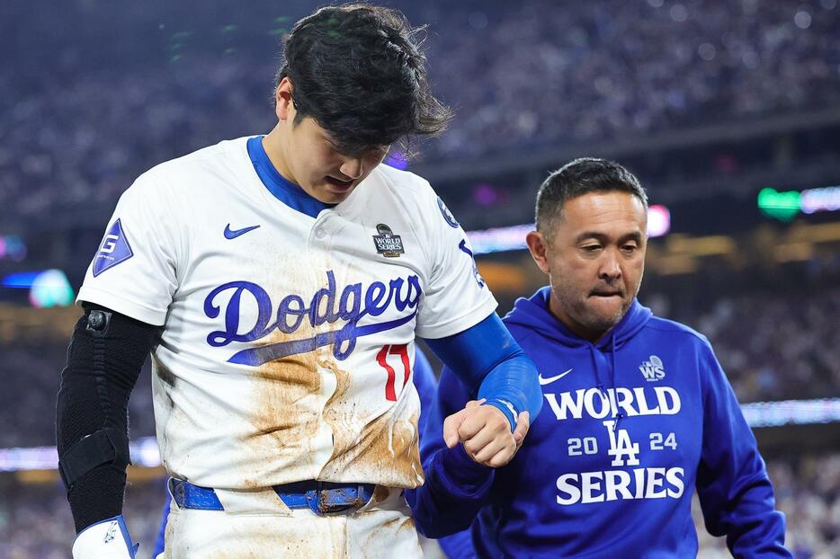 トレーナーに支えられ、ベンチ裏へと下がっていった大谷。(C)Getty Images